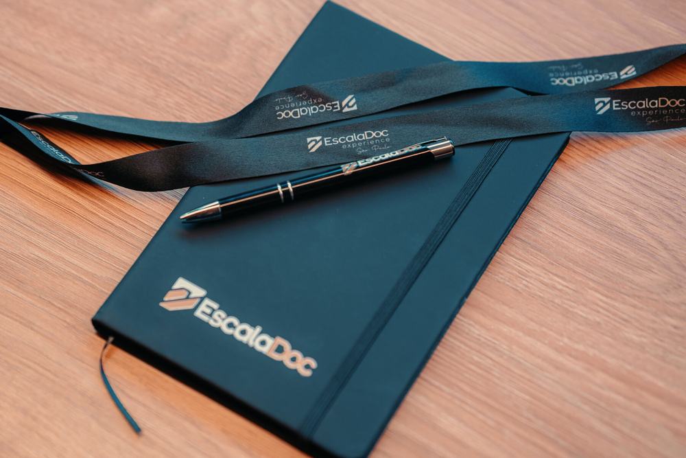 Caderno, caneta e crachá da EscalaDoc Experience
